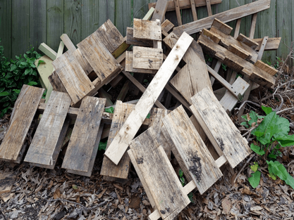 Wooden pallets piled up in yard against a fence in Wilmington Delaware